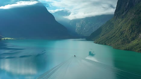 a cruise motorboat crosses a wide lake with turquoise waters of loenvatnet