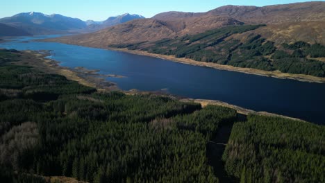 Slow-high-altitude-flight-over-dense-pine-forest-towards-Loch-Loyne-Scottish-Highlands