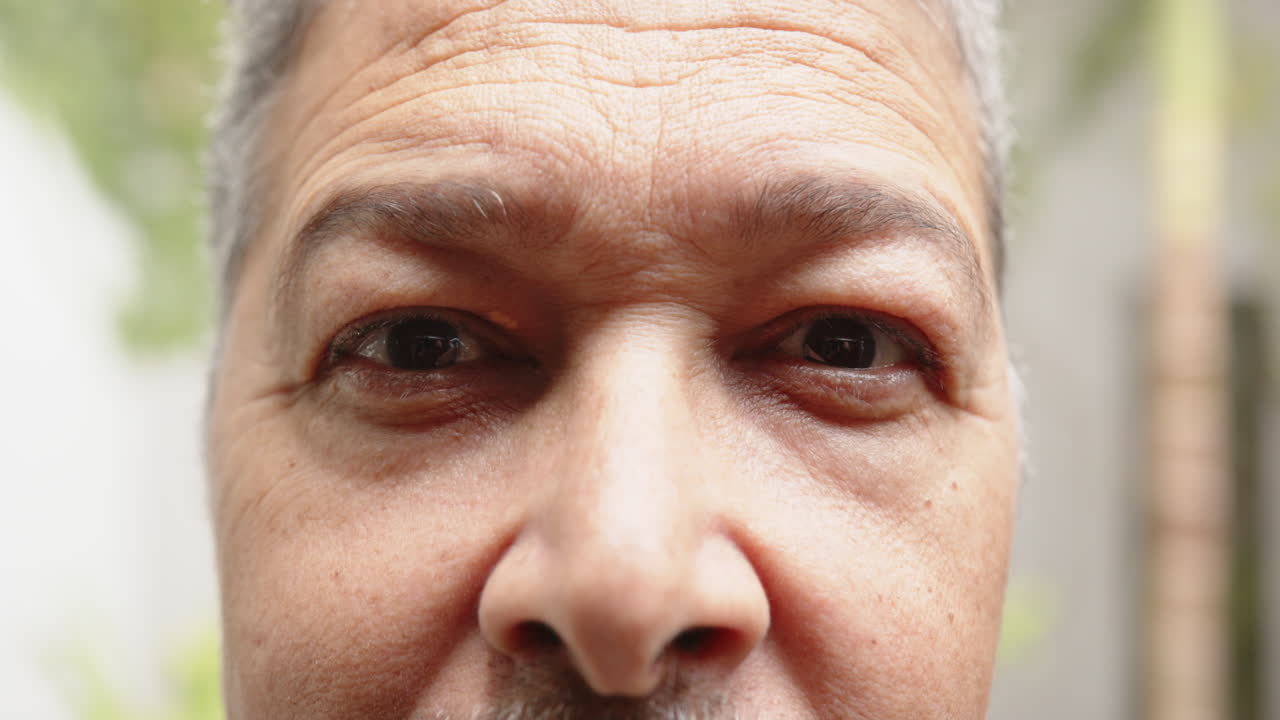 Close-up of person's face with neutral expression, focusing on features, at home