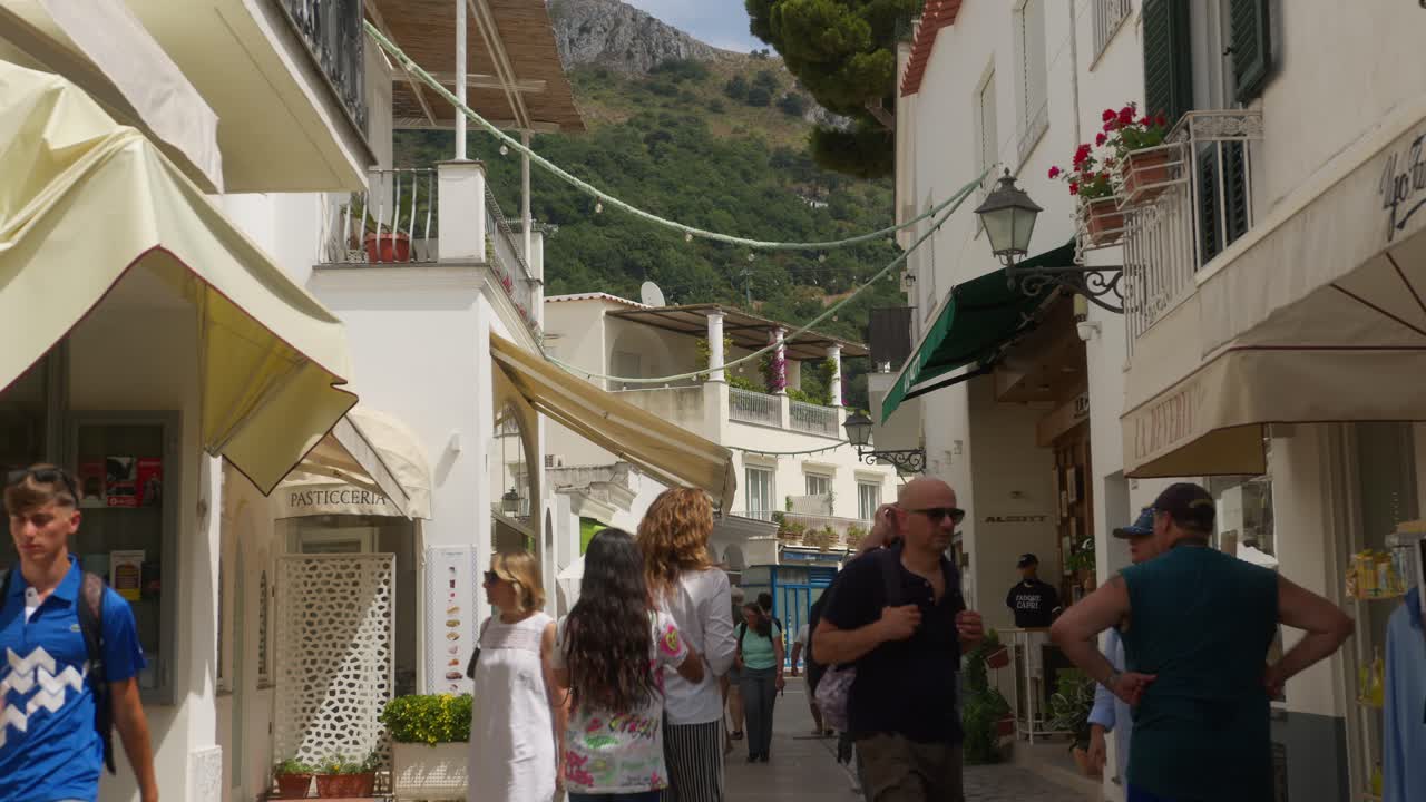 Tourists wander Anacapri's busy, white-architecture streets on a bright summer day