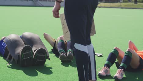 coach watching female hockey players exercising on the field