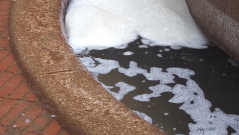 un primer plano de la espuma de la fuente con agua de lluvia entrando en ella en hong kong, china