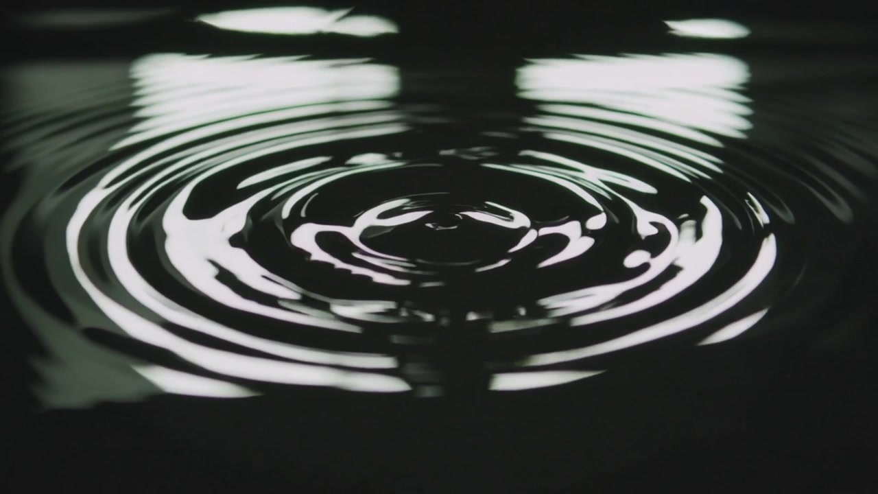 Goccia che colpisce la superficie dell'acqua in una stanza buia, creando anelli che si allargano, luce dalla finestra, banda verticale