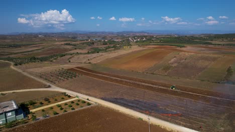 rural village agriculture: tractor at work on agricultural parcels, managing land and burning dry straw