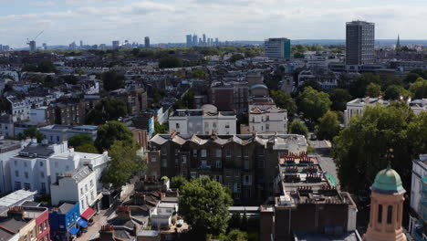 Forwards-fly-over-church-with-clock-tower-in-urban-neighbourhood.-Ascending-footage-revealing-cityscape.-London,-UK