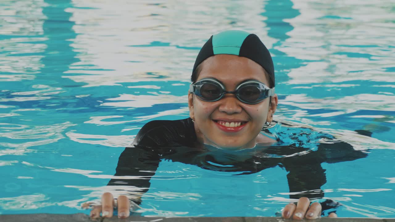 Young Asian Woman Wear Cap and Goggle Learning To Swim Holding Side Of Pool And Move Legs Under Water