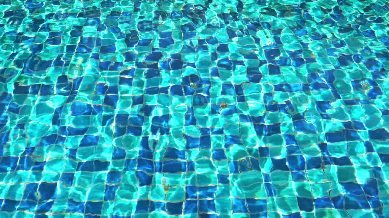 Shiny Water ripples in the swimming pool decorated with tiled mosaic