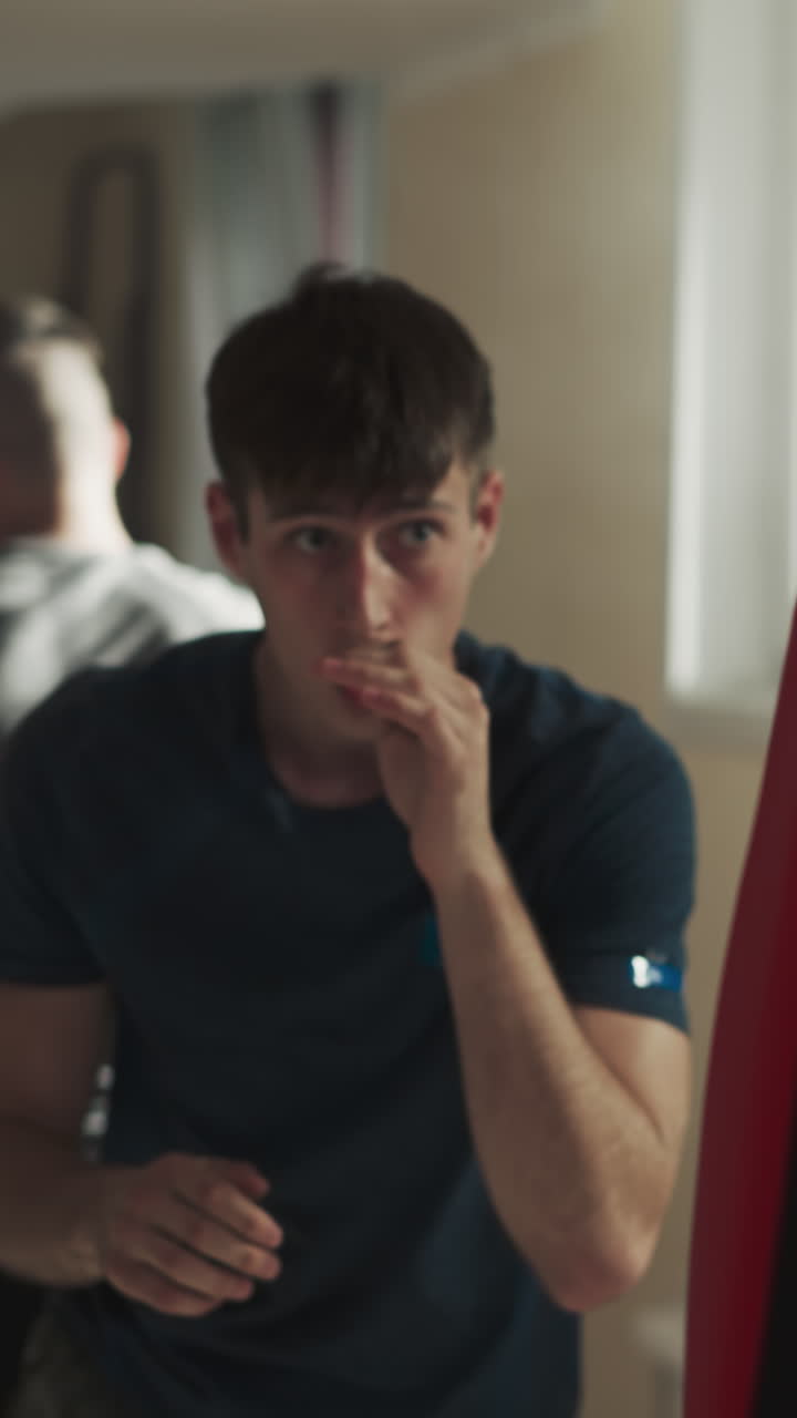 un fuerte joven boxeador muestra una fuerte técnica de golpe de pierna usando equipo especializado y saco de boxeo. sesión de entrenamiento en grupo en un gimnasio oscuro. instrucción del entrenador a los participantes