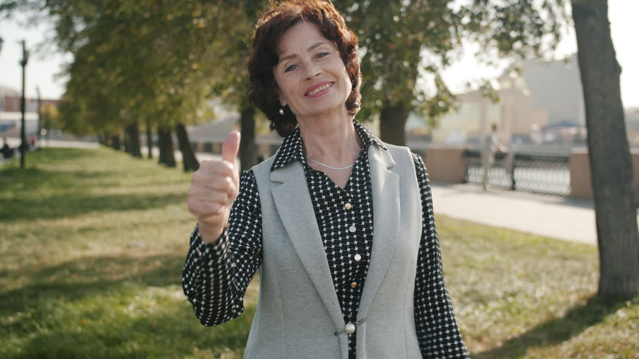 una mujer mayor sonriente levantando el pulgar.