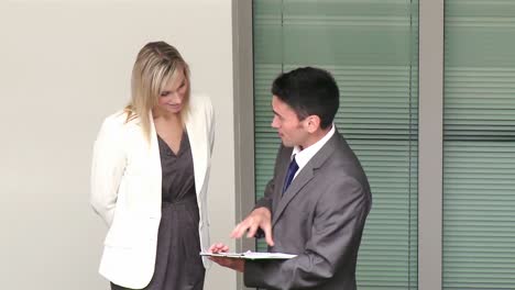 businessman and businesswoman talking about work in corridor