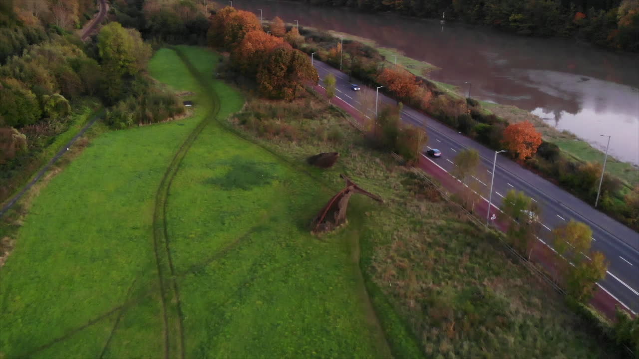Drone reverses away from whale art instilation at Bristol nature reserve alongside River Avon and A4 Portway during autumn