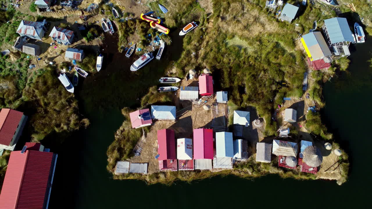 drone vista general de arriba hacia abajo de la isla de uros casas flotantes en el lago titicaca en aguas oscuras