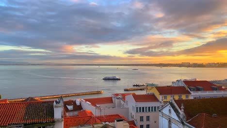 beautiful sunset view from a window on a river with moving boats with traditional orange rooftops and incredible sky in lisbon city portugal, 4k static shot