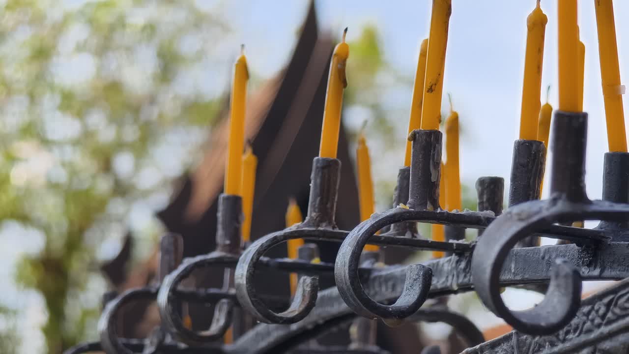 Candele gialle in un portacandele di metallo in un tempio