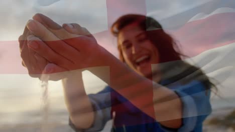 Animation-Der-Wehenden-Flagge-Englands-über-Einer-Frau,-Die-Spaß-Am-Strand-Hat