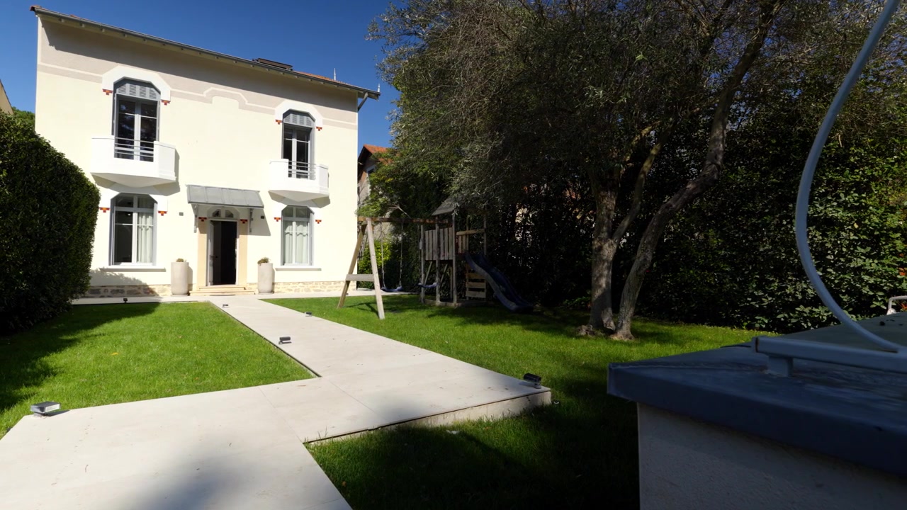 La Telecamera Scorre a Sinistra Oltre un Giardino Soleggiato e un'Elegante Casa Bianca a La Rochelle