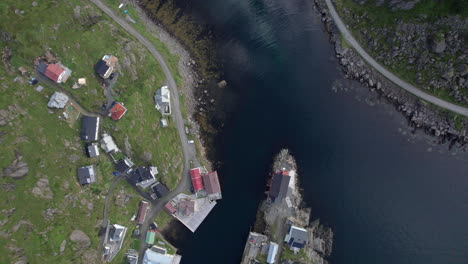 Birds-Eye-view-of-a-historical-fishing-village-in-Northern-Norway,-Nyksund,-clouds-reflecting-on-the-calm-water-surface-inside-the-harbor