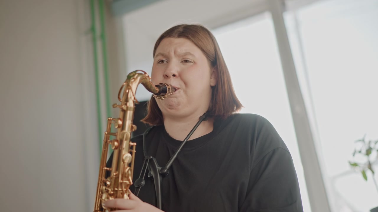 情熱的に演奏するミュージシャン。表現豊かな音楽パフォーマンスを捉えたサックス奏者の鮮明な写真。才能あるミュージシャンが、活気あるレコーディング環境で情熱的に楽器と向き合っています。