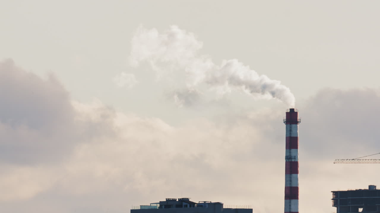 Skyline urbano con edifici residenziali e un camino industriale che emette fumo
