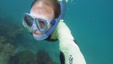 male diver surfaces from underwater with bubbles surrounding him