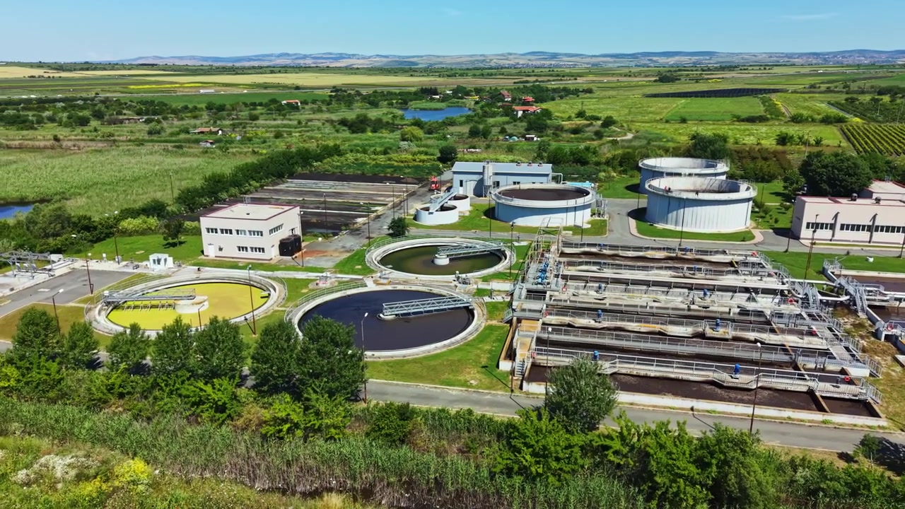Water treatment plant located in a rural area with structures and green land around, showing water processing activities on a clear day