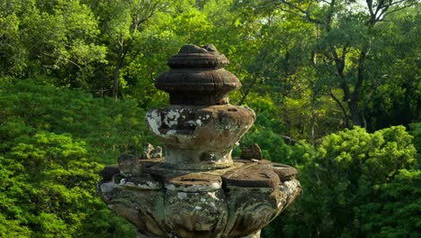 ancient stone monument covered in moss rising above lush jungle in angkor thom