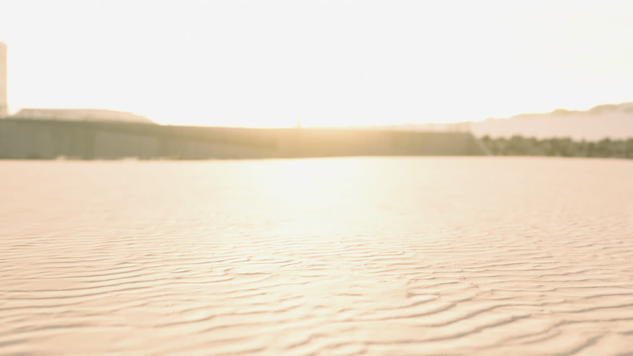 Soft sunlight illuminates the sandy terrain of a tranquil desert at dawn