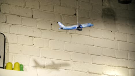 decorative airplane hanging from white brick wall