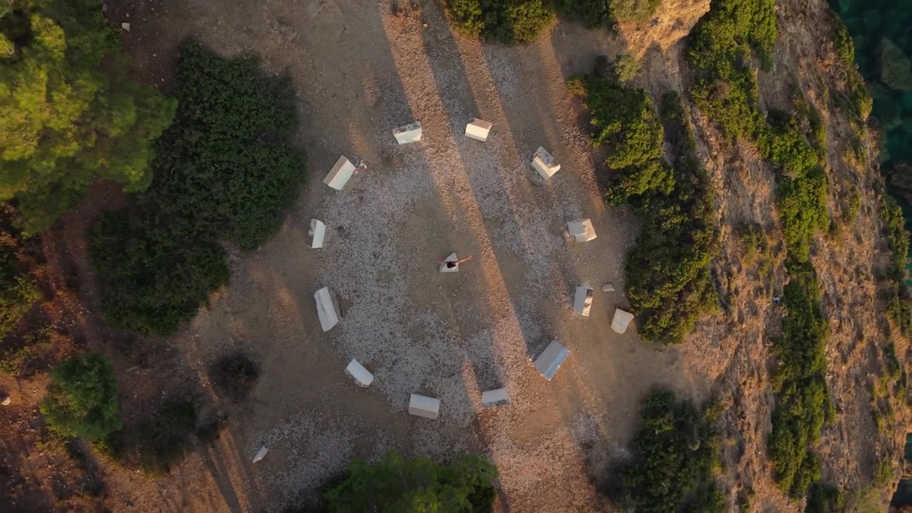 Ripresa aerea con drone di una donna che volteggia alla Corona di Limenaria, rivelando la costa circostante e il mare blu profondo di Thassos.