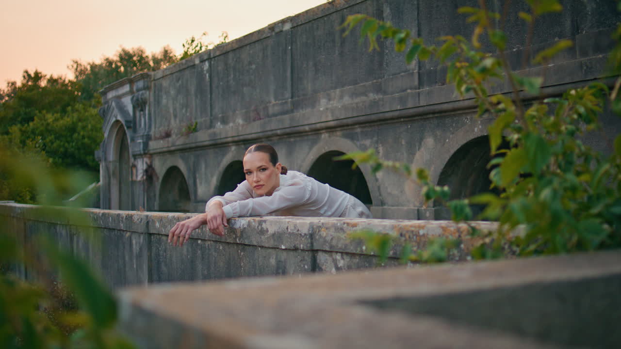 mujer inclinada balcón de piedra relajándose en el palacio medieval. chica de pie castillo