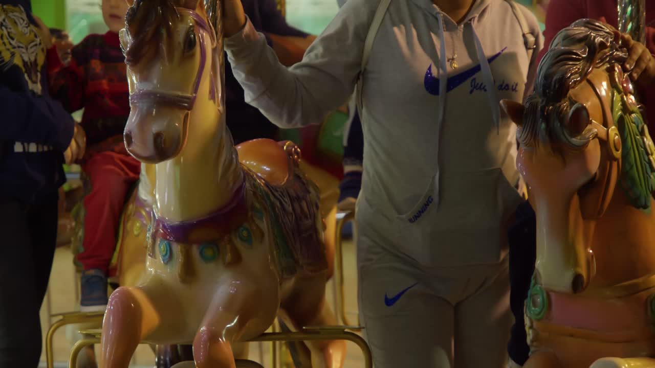 Parents assisting kids on a carousel ride in slow motion
