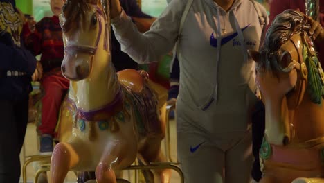 parents assisting kids on a carousel ride in slow motion