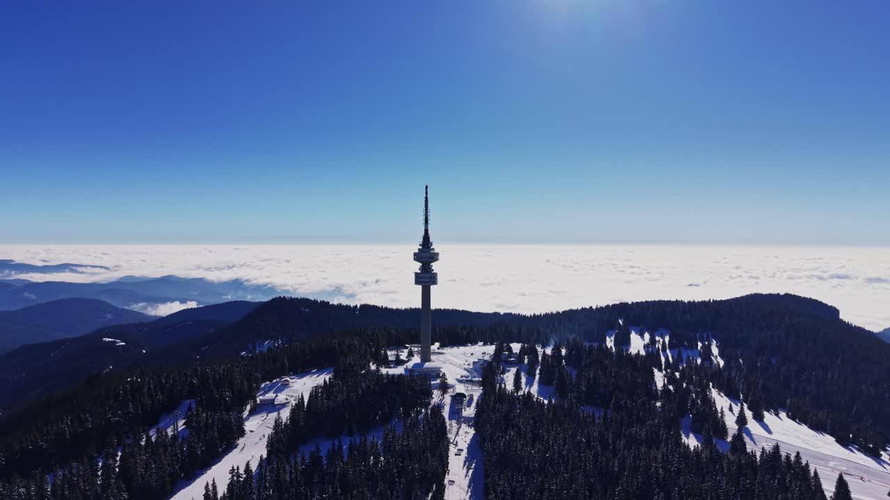 Snedækkede bjerge i Karpaterne med et kommunikationstårn og klar himmel.