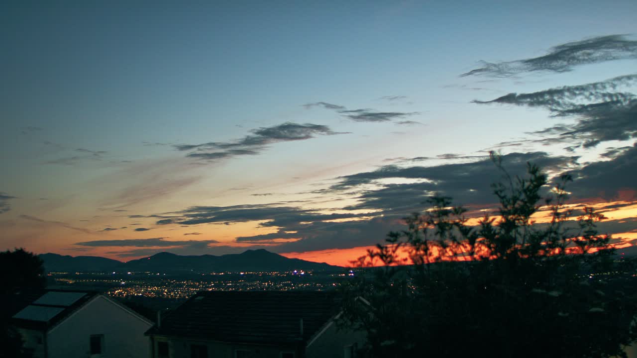 Pôr do sol em timelapse sobre as Pentland Hills perto de Edimburgo, Escócia, com as luzes da cidade surgindo abaixo da linha do cume, transitando da hora dourada para a hora azul.