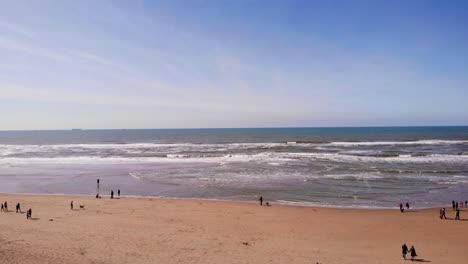 Gente-Caminando-En-La-Playa-De-Katwijk-Aan-Zee-Con-Olas