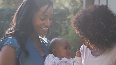 Grandmother-With-Adult-Daughter-And-Baby-Granddaughter-Playing-In-Garden-At-Home-Together