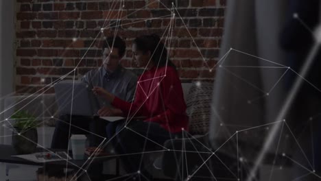 animación de la red sobre un colega masculino y femenino usando una computadora portátil en el sofá de la oficina