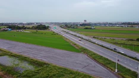 Cars-Driving-On-The-Expressway-By-The-Lush-Green-Paddy-Fields-In-Bangkok,-Thailand