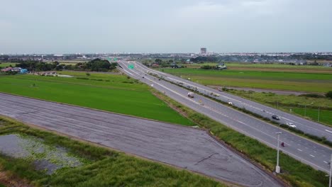 coches circulando por la autopista junto a los exuberantes arrozales verdes en bangkok, tailandia