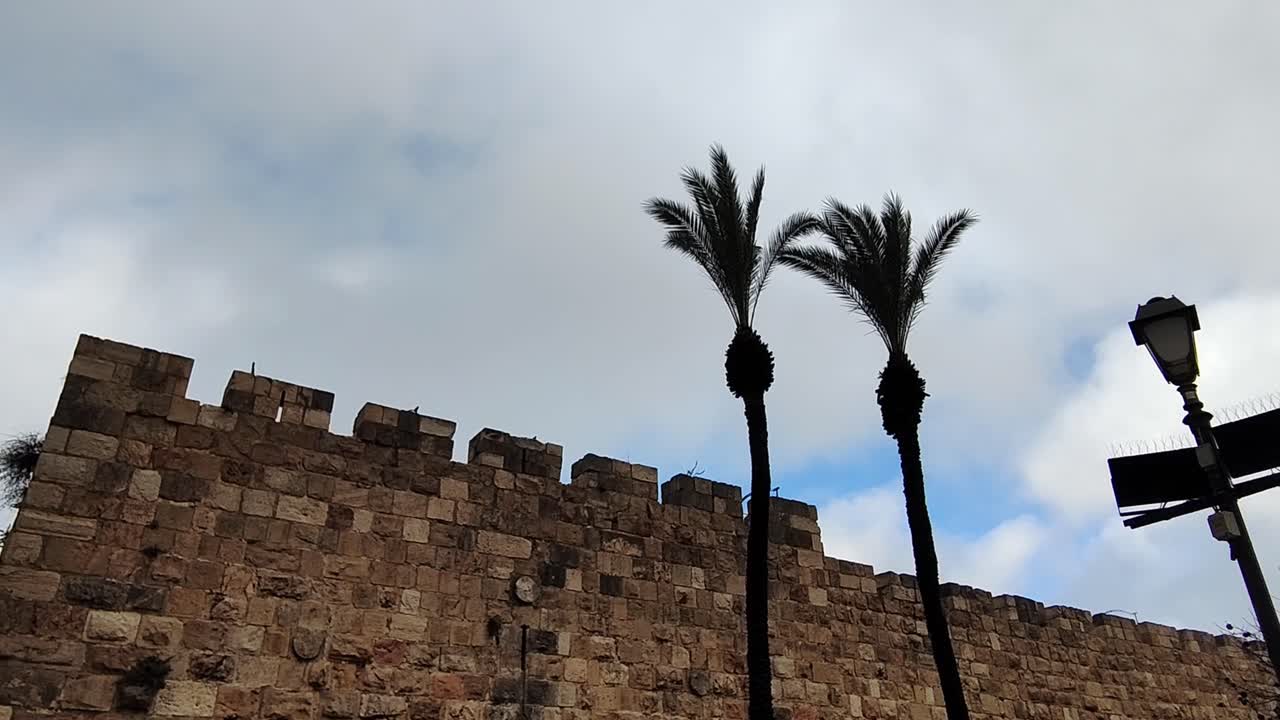 A wall made of stone blocks with a building in the background. Jerusalem old city wall.