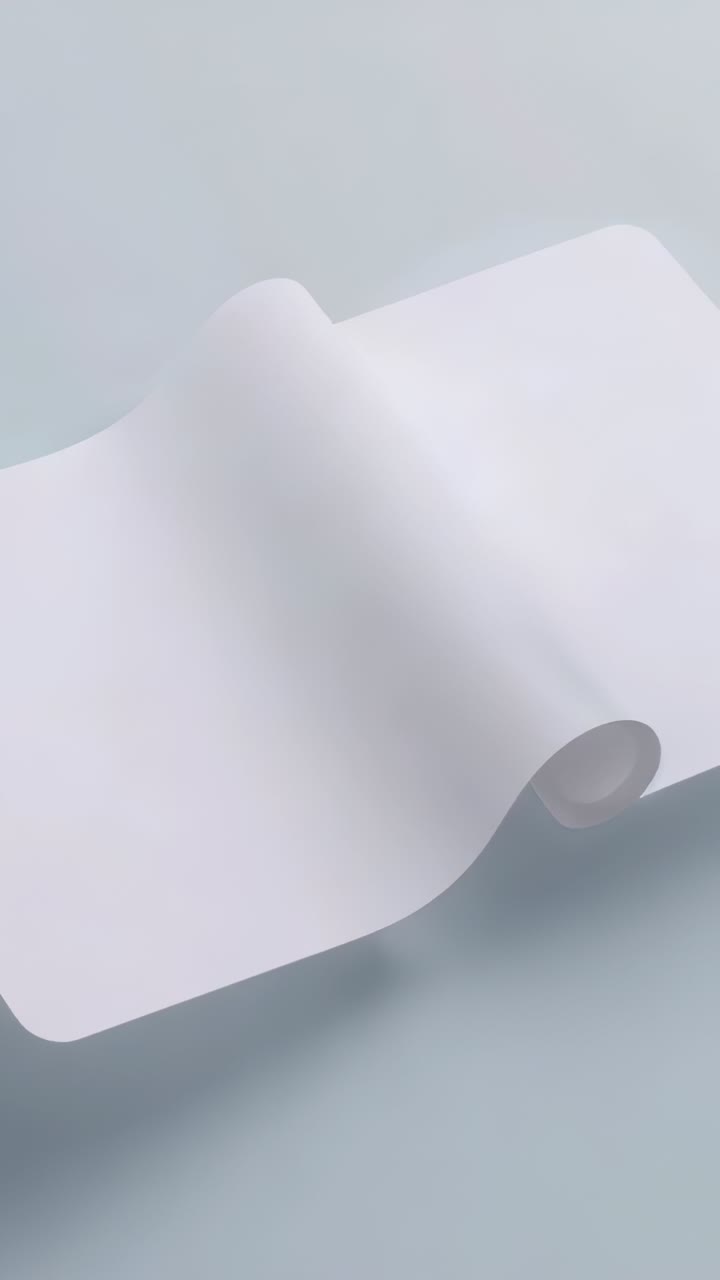 Vertical video: Shifting white paper roll unrolling on pale blue surface, revealing cardboard core