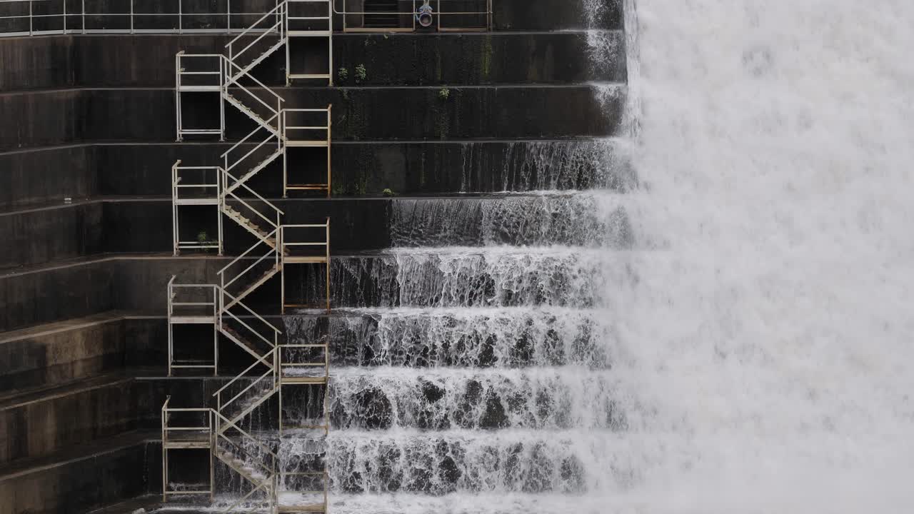 Tight view of water flowing through the Hinze Dam overflow and dam steps due to ongoing heavy rains in the Gold Coast Hinterland