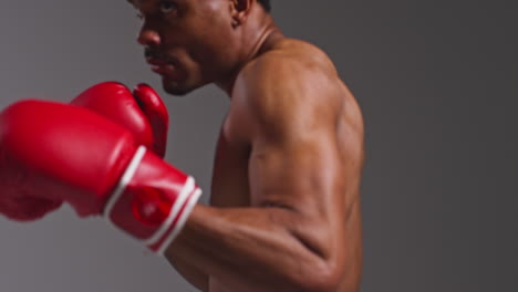 Close-Up-Studio-Shot-Of-Tattooed-Male-Boxer-Wearing-Boxing-Gloves-In-Boxing-Match-Throwing-Punches