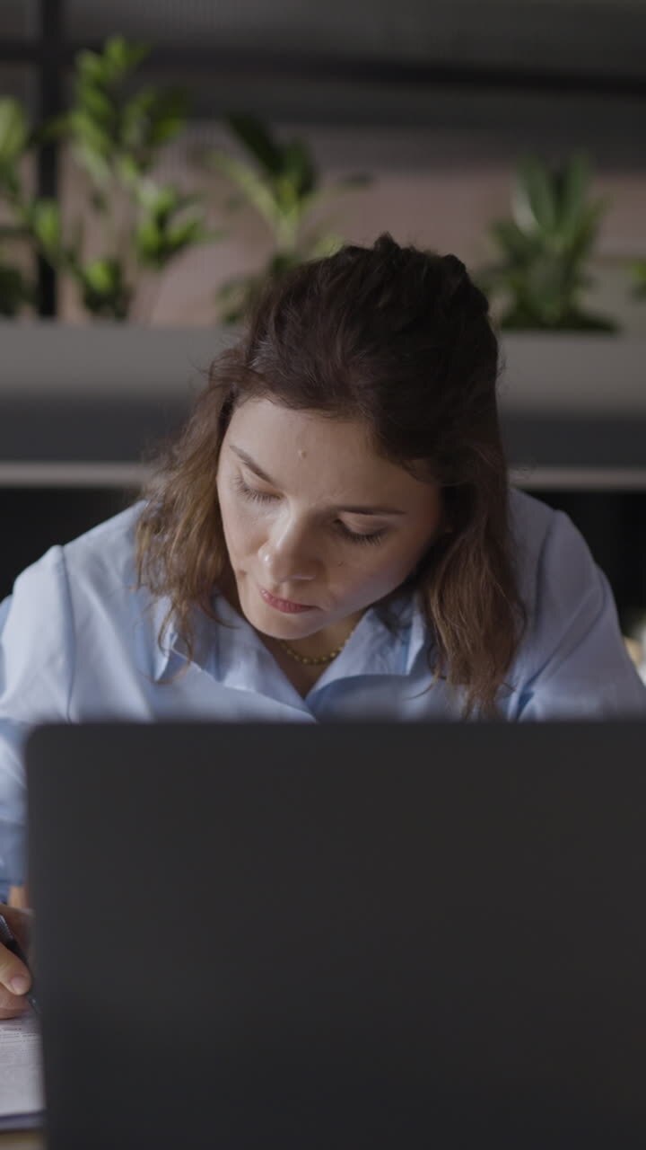 mujer trabajando en una computadora portátil y documentos en un entorno de oficina