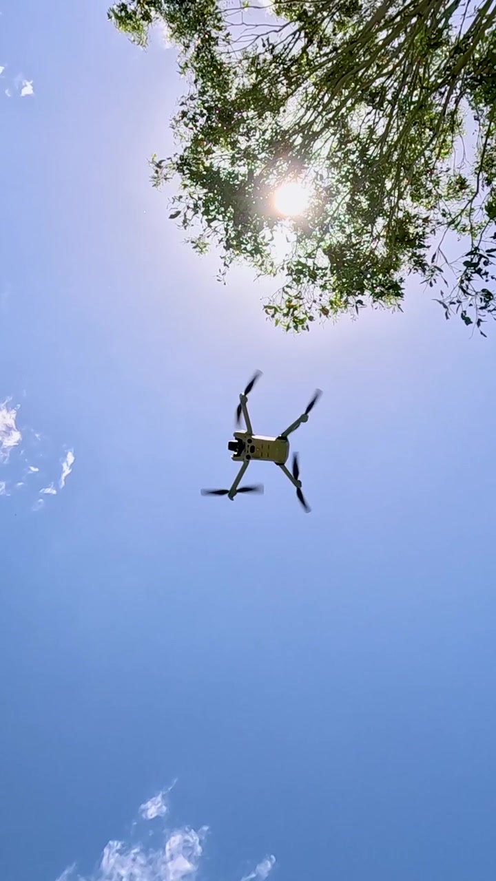 Drone flying upward through clear blue sky