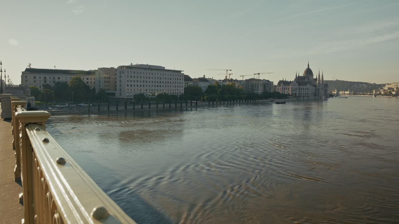 Passerella lungofiume allagata lungo il Danubio con il Parlamento ungherese in lontananza durante l'alluvione di Budapest del 2024.