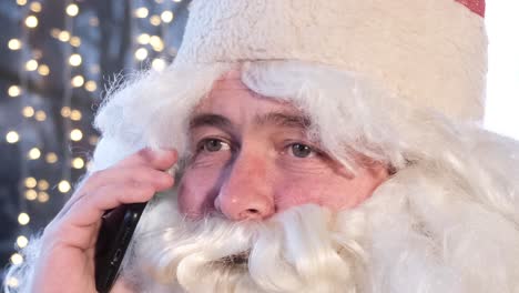 santa claus uses a smartphone while sitting in a cafe he is resting and talking on the phone santa claus uses a smartphone while sitting in a cafe he is resting and talking on the phone funny santa claus