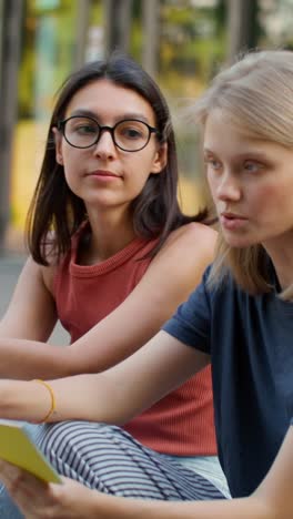 two young women studying outdoors