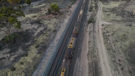 Drones-Volando-Sobre-Un-Tren-De-Carga-De-Combustible-Que-Pasa-Por-Un-Paisaje-Rural,-En-El-Oeste-De-Australia