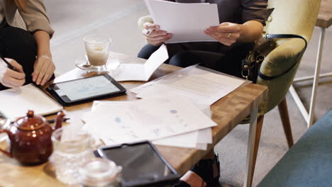 mujeres de negocios se reúnen en una cafetería usando una tableta digital